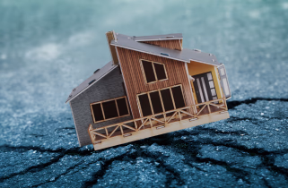 miniature of a house on cracked asphalt portraying the concept of an earthquake