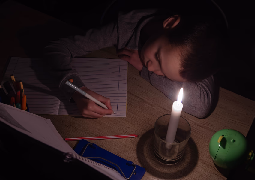 child doing homework by candlelight