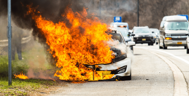 car on side of highway covered in flames
