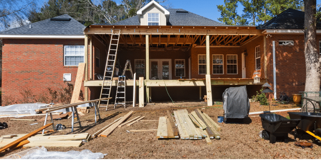 back of home with lumber stacks in yard