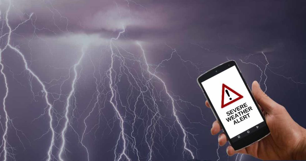 hand holding cell phone with lightning strikes as background