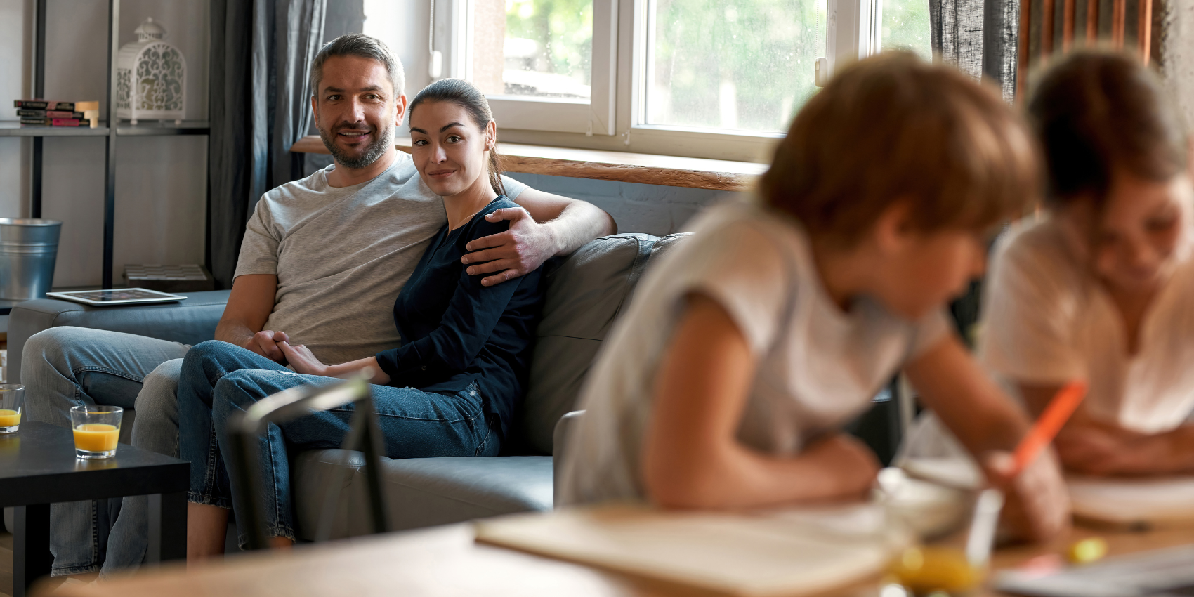Parents on sofa watching kids do homework