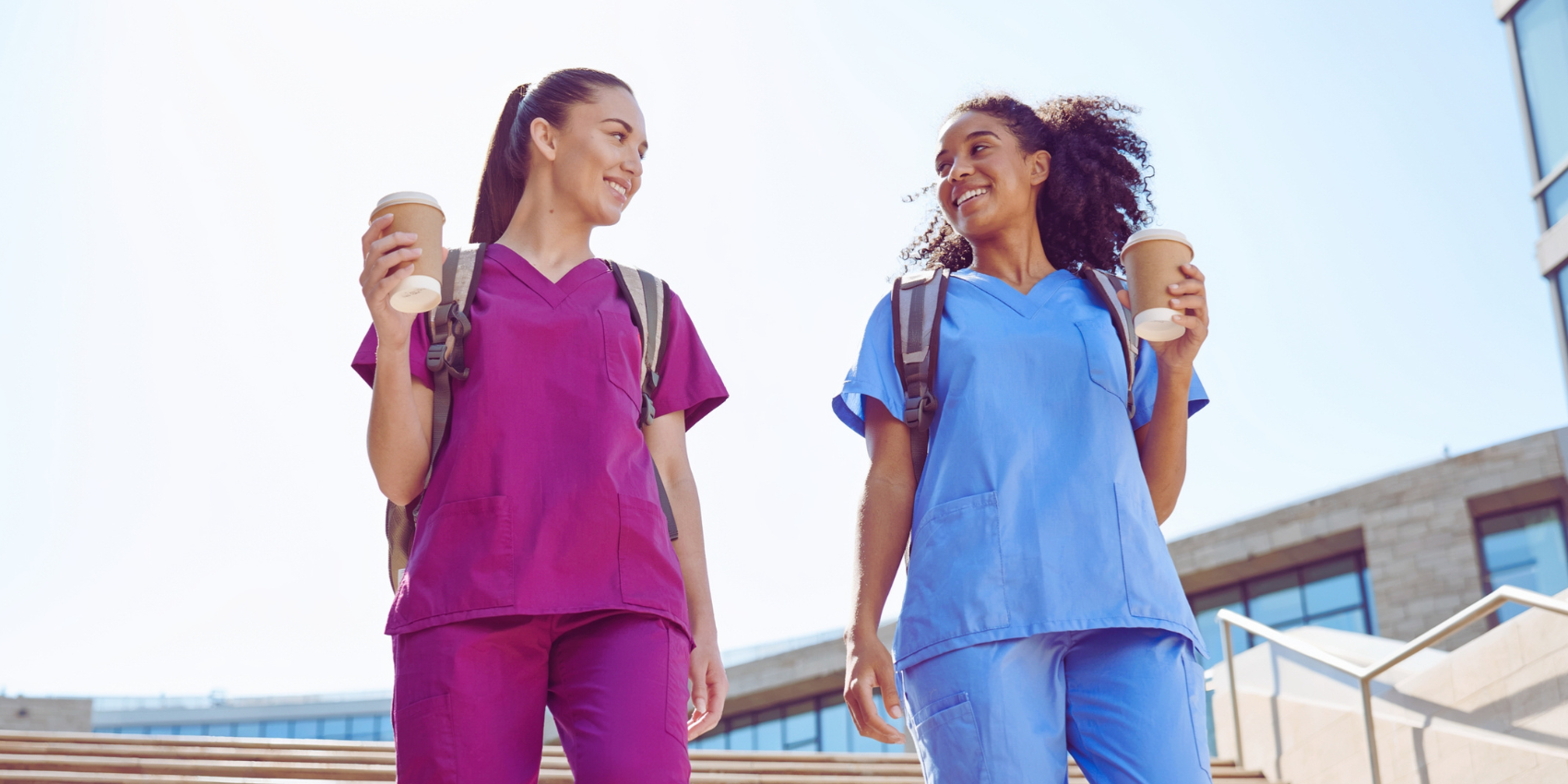 two nurses facing each other with coffees in hand.