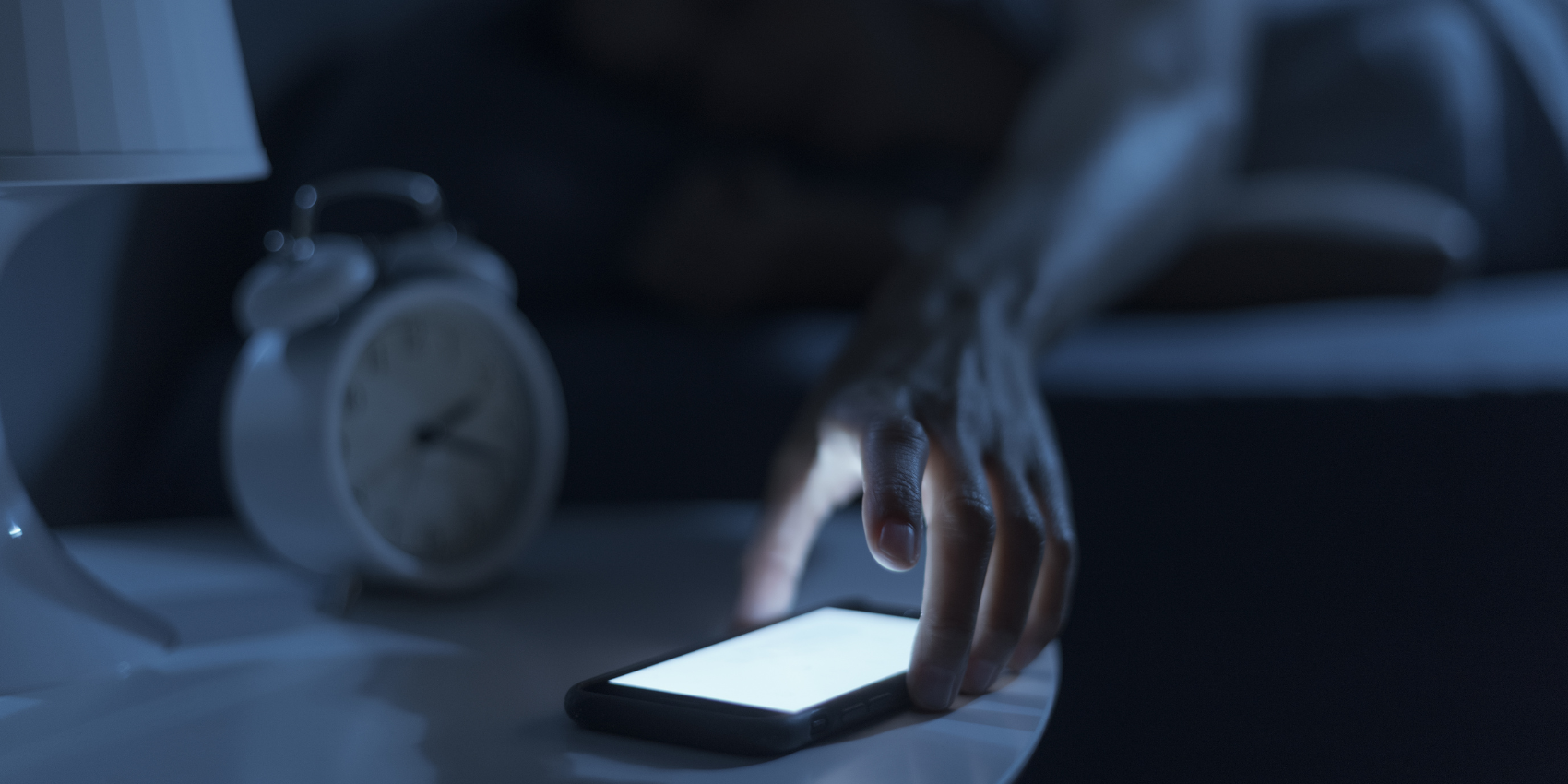 person reaching for phone in the dark